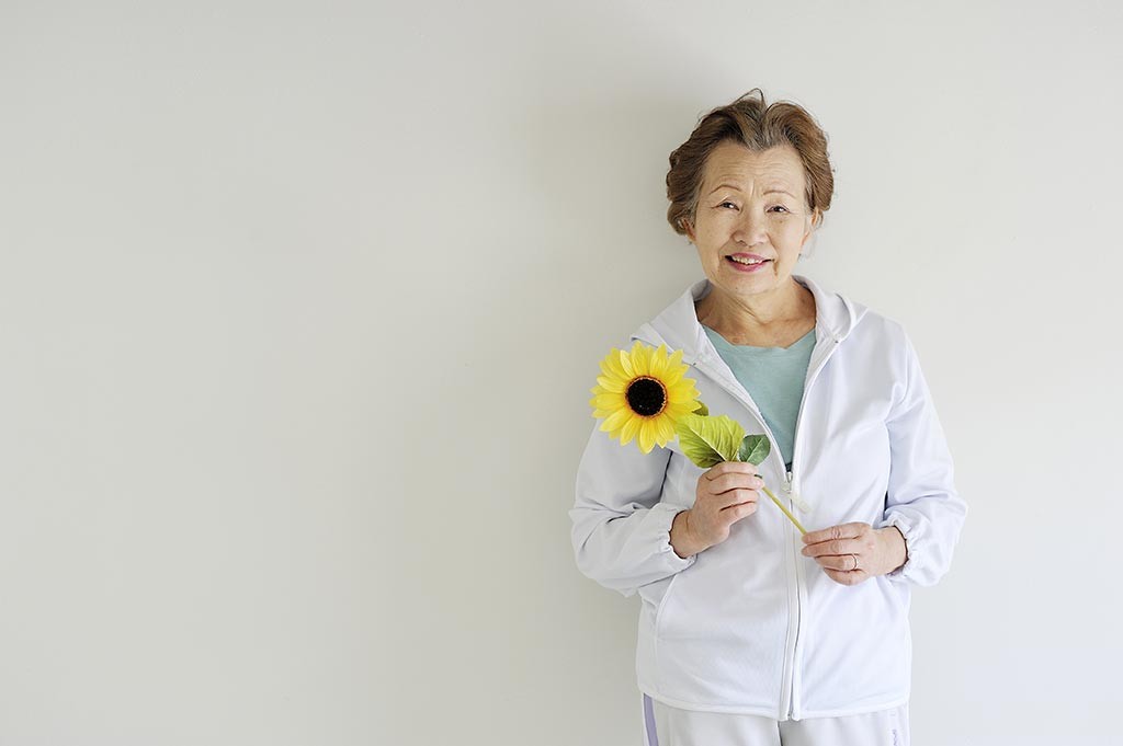 Older Asian lady holding a sunflower